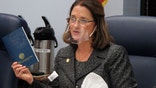 FILE - In this Jan. 27, 2021 file photo, Alaska state Sen. Lora Reinbold, an Eagle River Republican, holds a copy of the Alaska Constitution during a committee hearing in Juneau, Alaska. Alaska Airlines has banned the Alaska state senator for refusing to follow mask requirements. Last week Reinbold was recorded in Juneau International Airport arguing with Alaska Airlines staff about mask policies. A video posted to social media appears to show airline staff telling Reinbold her mask must cover her nose and mouth. Reinbold has been a vocal opponent to COVID-19 mitigation measures and has repeatedly objected to Alaska Airlines' mask policy, which was enacted before the federal government's mandate this year. (AP Photo/Becky Bohrer, File)
