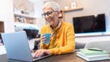Senior woman working at home using laptop computer in the living room