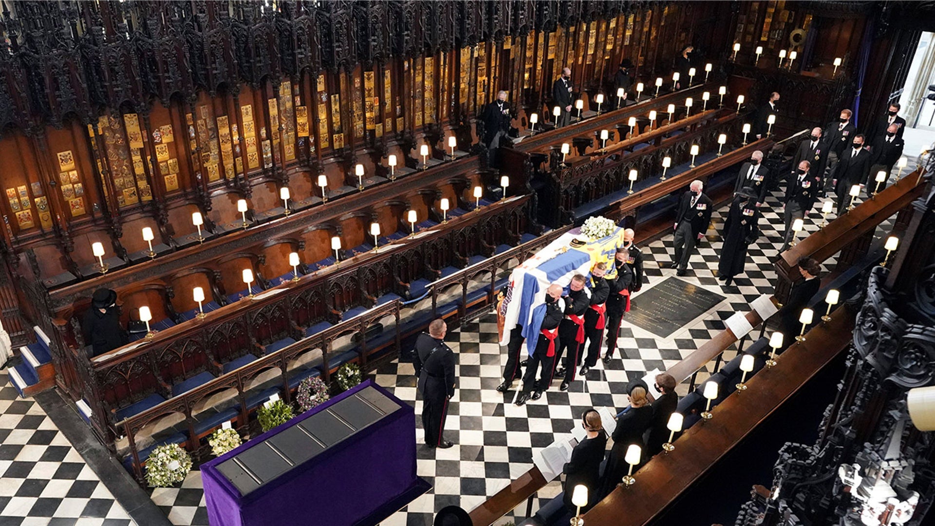 Queen Elizabeth II watches as pallbearers carry the coffin of the Duke of Edinburgh during his funeral at St. George's Chapel in Windsor Castle. Picture date: Saturday April 17, 2021. PA Photo. Following the coffin are the Prince of Wales, the Princess Royal, the Earl of Wessex, the Duke of York, Mr Peter Phillips, the Duke of Cambridge, the Earl of Snowdon, the Duke of Sussex and Vice Admiral Sir Tim Laurence. See PA story FUNERAL Philip. Photo credit should read: Dominic Lipinski/PA Wire