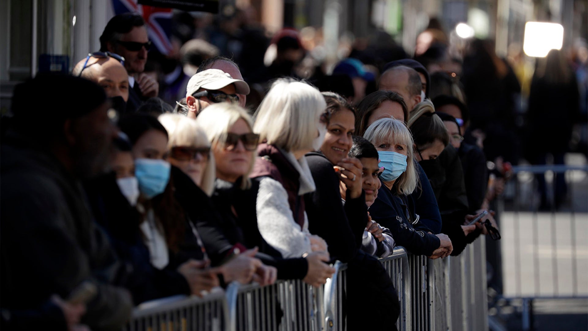 People wait by barriers outside Windsor Castle ahead of the funeral of Britain's Prince Philip in Windsor, England, Saturday, April 17, 2021. Philip died April 9 at the age of 99 after 73 years of marriage to Britain's Queen Elizabeth II. Due to coronavirus restrictions, there will be only 30 mourners for the service, including the widowed queen, her four children and eight grandchildren. (AP Photo/Matt Dunham)