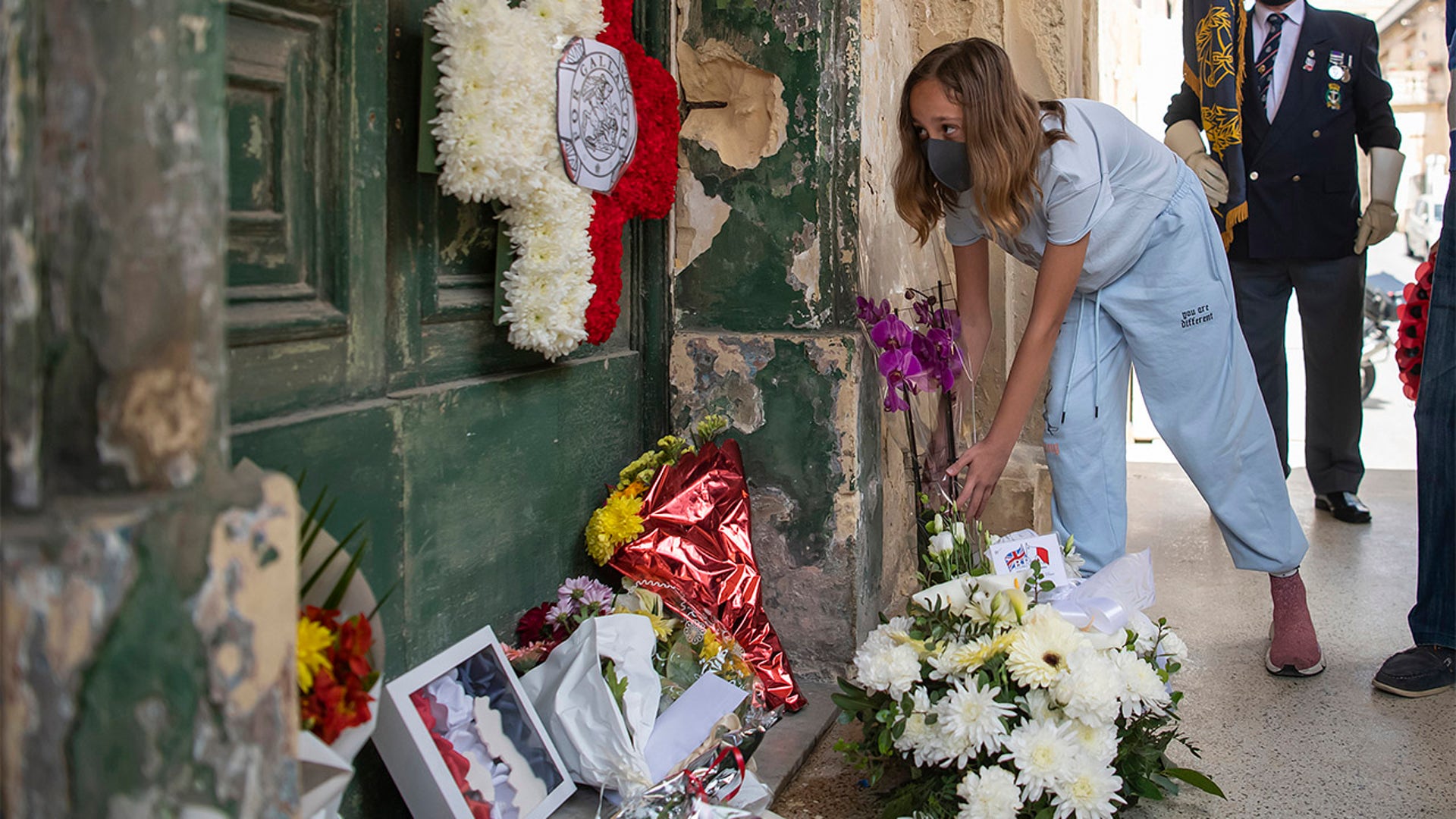 A woman lays flowers outside the old residence of Prince Phillip, Villa Guardamangia in Pieta, in Valletta, Malta, Saturday, April 17, 2021. Prince Philip, husband of Queen Elizabeth II, died Friday April 9 aged 99. His funeral service is taking place at St. George's Chapel inside Windsor Castle Saturday. (AP Photo/Rene' Rossignaud)