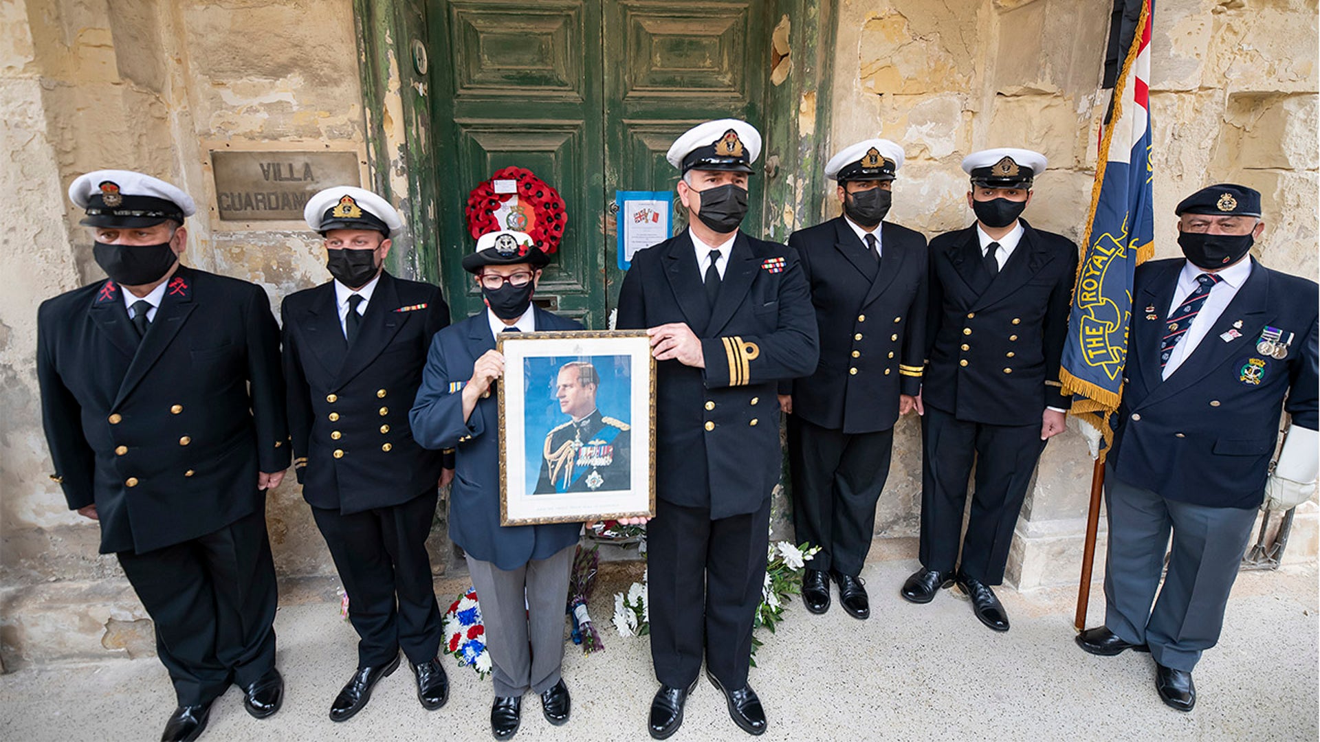 Maltese Navy officers hold a picture of Prince Phillip, outside his former residence, Villa Guardamangia in Pieta, in Valletta, Malta, Saturday, April 17, 2021. Prince Philip, husband of Queen Elizabeth II, died April 9 at the age of 99. His funeral service is taking place Saturday at St. George's Chapel in Windsor Castle. (AP Photo/Rene' Rossignaud)
