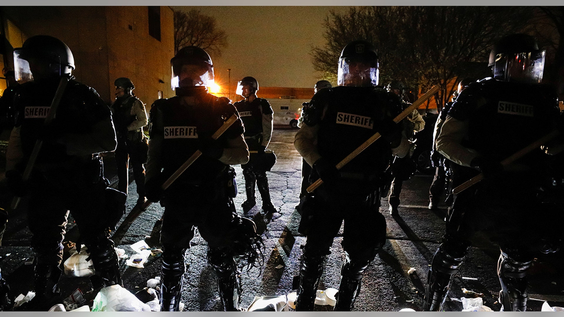 Officers stand guard outside Brooklyn Center Police Department with trash thrown at them by demonstrators at their feet after police allegedly shot and killed a man who local media report is identified by the victim's mother as Daunte Wright, in Brooklyn Center, Minnesota, April 11, 2021.