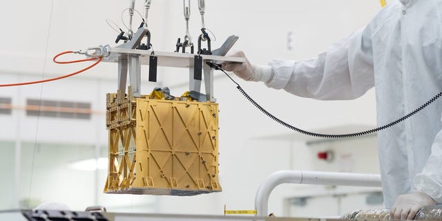 Technicians at NASA’s Jet Propulsion Laboratory lower the Mars Oxygen In-Situ Resource Utilization Experiment (MOXIE) instrument into the belly of the Perseverance rover.