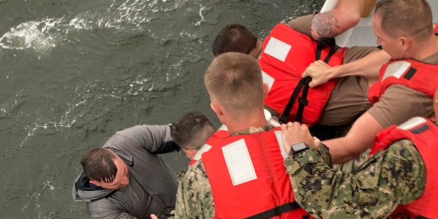 Crew members of the Coast Guard Cutter Glenn Harris pull a person from the water on Tuesday, April 13, 2021 after a commercial lift boat capsized 8 miles south of Grand Isle, La. (AP/U.S. Coast Guard)