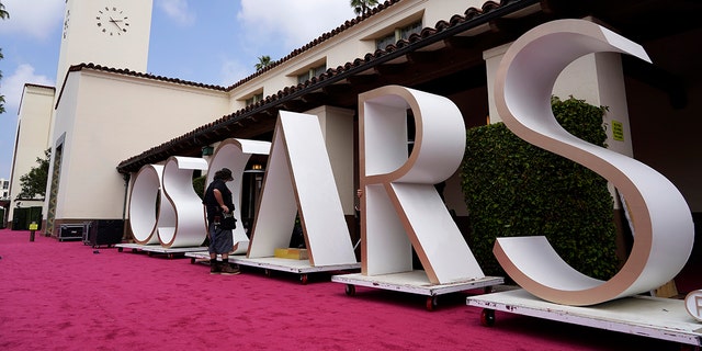 An Academy Awards crew member looks over a background element for the red carpet at Union Station, one of the locations for Sunday's 93rd Academy Awards, Saturday, April 24, 2021, in Los Angeles.