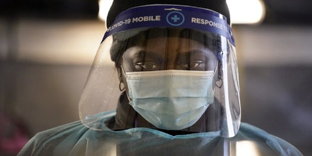 In this Dec. 8, 2020, file photo, a health care worker wears personal protective equipment as she speaks to a patient at a mobile testing location for COVID-19 in Auburn, Maine. (AP Photo/Robert F. Bukaty, File)