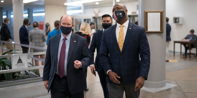 Members of the Senate Committee on Small Business, Sen. Chris Coons, D-Del., left, talks with Sen. Tim Scott, R-S.C., as senators head to the chamber for a procedural vote on the nomination of Shalanda Young to be deputy director of the Office of Management and Budget, at the Capitol in Washington, Tuesday, March 23, 2021. (AP Photo/J. Scott Applewhite)
