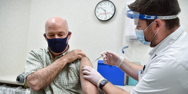 Gov. Greg Gianforte receives a shot of the Pfizer COVID-19 vaccine from pharmacist Drew Garton at a Walgreen's pharmacy, Thursday, April 1, 2021, in Helena, Montana.  (Thom Bridge/Independent Record via AP)