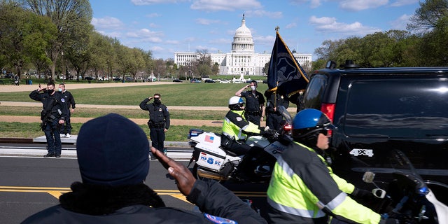 With the U.S. Capitol in the background, U.S. Capitol Police officers salute as procession carries the remains of a U.S. Capitol Police officer who was killed after a man rammed a car into two officers at a barricade outside the Capitol in Washington, Friday, April 2, 2021. (AP Photo/Jose Luis Magana)