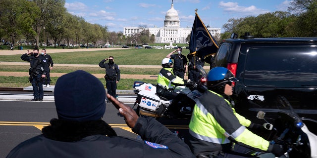 With the U.S. Capitol in the background, U.S. Capitol Police officers salute as procession carries the remains of a U.S. Capitol Police officer who was killed after a man rammed a car into two officers at a barricade outside the Capitol in Washington, Friday, April 2, 2021. (AP Photo/Jose Luis Magana)