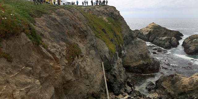 Bodega Bay firefighters are working to secure the scene of an accident after a vehicle from the Bodega Head car park in Bodega Bay, California, fell through a wooden barrier, landed left and upside down 100 feet to the rocky shore and two people in the SUV, Saturday, April 3, 2021. (Kent Porter / The Press Democrat via AP)