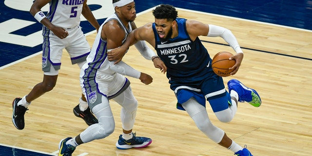 Minnesota Timberwolves center Karl-Anthony Towns (32) is fouled by Sacramento Kings center Richaun Holmes during the first half of an NBA basketball game Monday, April 5, 2021, in Minneapolis. (AP Photo/Craig Lassig)