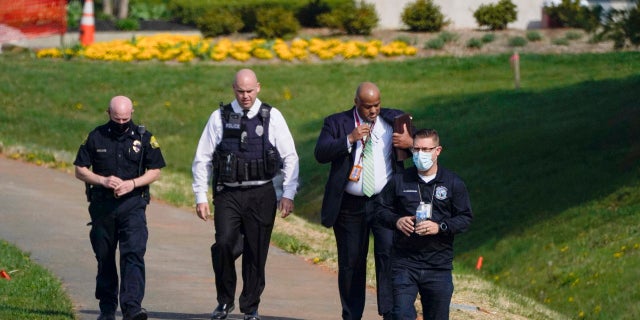 Police walk near the scene of a shooting at a business park in Frederick, Md., Tuesday, April 6, 2021. (AP Photo/Julio Cortez)
