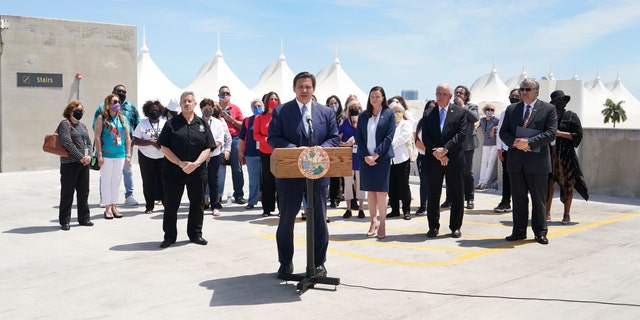 Florida Gov. Ron DeSantis, center, speaks during a news conference surrounded by cruise workers on April 8 at the Port of Miami in Miami. DeSantis announced a lawsuit against the federal government and the CDC demanding that cruise ships be allowed to sail. (AP Photo/Wilfredo Lee)