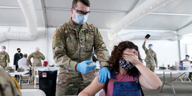 Leanne Montenegro, 21 ans, se couvre les yeux car elle n'aime pas la vue des aiguilles, alors qu'elle reçoit le vaccin Pfizer COVID-19 dans un centre de vaccination FEMA du Miami Dade College, le lundi 5 avril 2021, à Miami.  (Photo AP / Lynne Sladky)