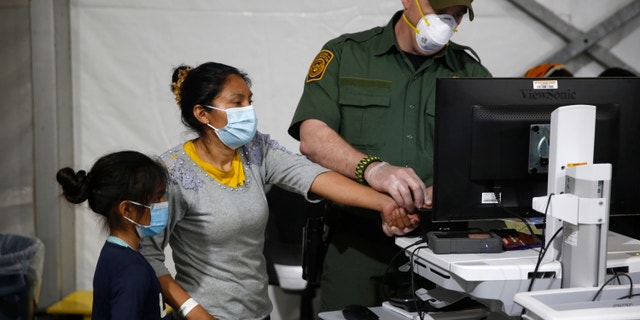 A migrant and her daughter have their biometric data entered at the intake area of the U.S. Department of Homeland Security holding facility, the main detention center for unaccompanied children in the Rio Grande Valley, in Donna, Texas, March 30, 2021.