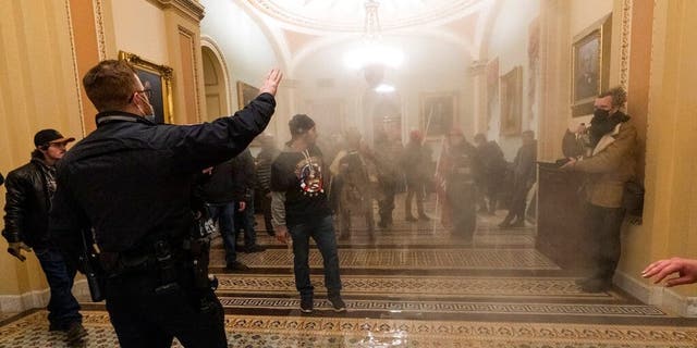 FILE - In this Jan. 6, 2021, file photo, smoke fills the walkway outside the Senate Chamber as violent rioters loyal to President Donald Trump are confronted by U.S. Capitol Police officers inside the Capitol in Washington. New details from the deadly riot of Jan. 6 are contained in a previously undisclosed document prepared by the Pentagon for internal use that was obtained by the Associated Press and vetted by current and former government officials. (AP Photo/Manuel Balce Ceneta, File)