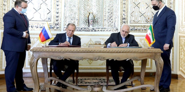 In this photo released by the Iranian Foreign Ministry, Iranian Foreign Minister Mohammad Javad Zarif, center right, and his Russian counterpart Sergey Lavrov, center left, sign agreements after their talks in Tehran, Iran, Tuesday, April 13, 2021. 