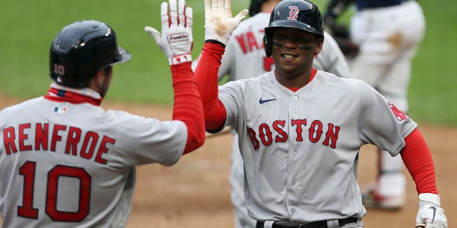 Boston Red Sox Rafael Devers (11) high fives teammate Boston Red Sox Hunter Renfroe (10) after hitting a home run against the Minnesota Twins during the ninth inning of a baseball game, Tuesday, April 13, 2021, in Minneapolis. Boston won 4-2.