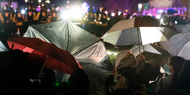 Demonstrators use umbrellas as shields against police during a clash outside the Brooklyn Center Police Department while protesting the shooting death of Daunte Wright, late Tuesday, April 13, 2021, in Brooklyn Center, Minn. (AP Photo/John Minchillo)