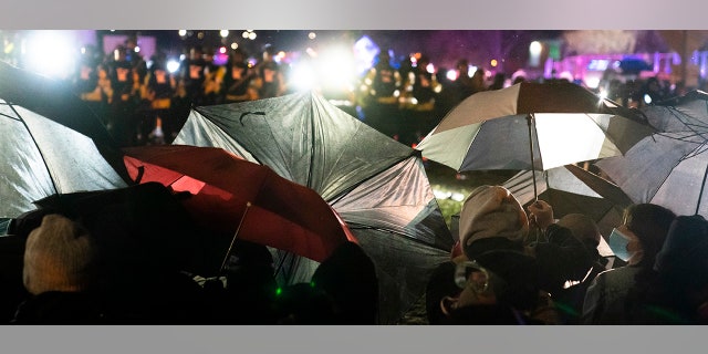 Demonstrators use umbrellas as shields against police during a clash outside the Brooklyn Center Police Department while protesting the shooting death of Daunte Wright, late Tuesday, April 13, 2021, in Brooklyn Center, Minn. (AP Photo/John Minchillo)