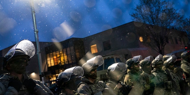 National Guardsmen stand behind a fenced perimeter as demonstrators gather near the Brooklyn Center Police Department on Tuesday, April 13, 2021, to protest Sunday's fatal shooting of Daunte Wright during a traffic stop in Brooklyn Center, Minn. (AP Photo/John Minchillo)