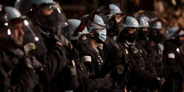 Police officers look on near Chicago Mayor Lori Lightfoot's home as people protest the shooting and killing of 13-year-old Adam Toledo by an officer Friday, April 16, 2021, in Chicago. (AP Photo/Paul Beaty)