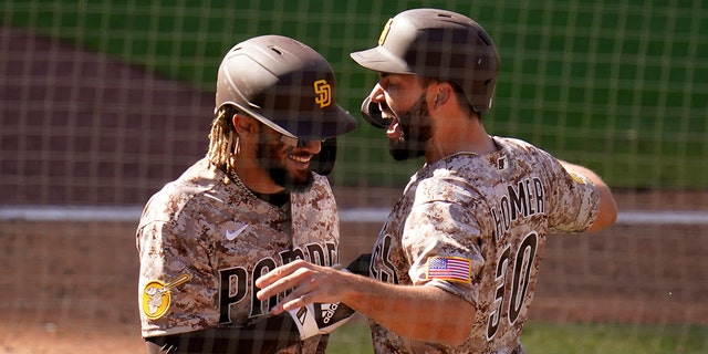 San Diego Padres' Eric Hosmer, right, celebrates with teammate Fernando Tatis Jr. after they both scored during the eighth inning against the Los Angeles Dodgers, April 18, 2021, in San Diego, California.