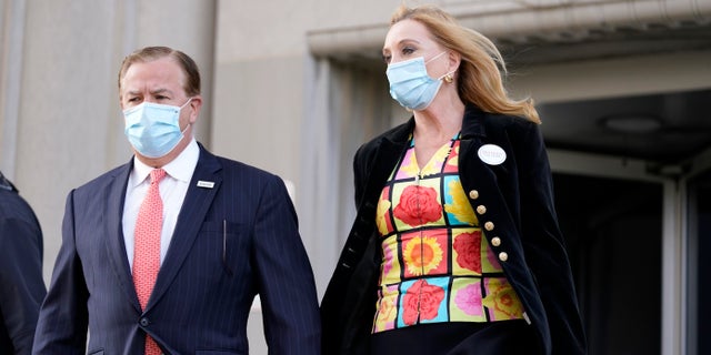 In this Oct. 14, 2020, file photo, Mark and Patricia McCloskey leave following a court hearing, in St. Louis. The couple, who face charges for waving guns at racial injustice protesters near their St. Louis home in June, are asking a judge to remand the case back to the grand jury for reconsideration. (AP Photo/Jeff Roberson)