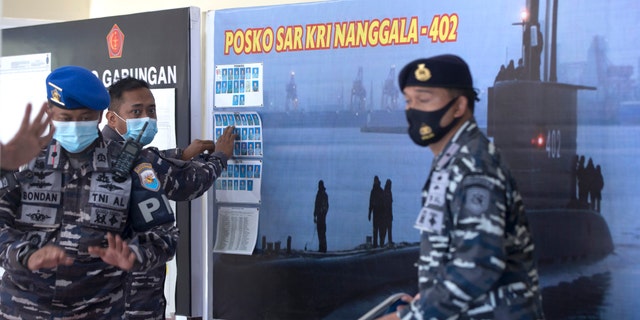 An Indonesian military official sets pictures of Indonesian Navy members on submarine KRI Nanggala that went missing while participating in a training exercise on Wednesday, at Ngurah Rai Airport, Bali, Indonesia, on Friday, April 23, 2021. (AP Photo/Firdia Lisnawati)