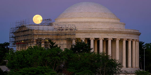 The moon rises over the scaffolding surrounding the entrance to the Jefferson Memorial, in Washington, late Monday, April, 26, 2021. The Jefferson Memorial is in the middle of a multi-year renovation project. (AP Photo/J. David Ake)