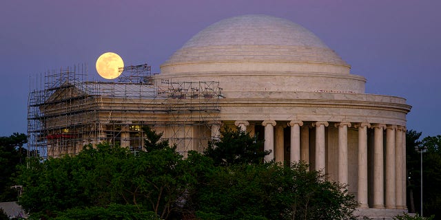 The moon rises over the scaffolding surrounding the entrance to the Jefferson Memorial, in Washington, late Monday, April, 26, 2021. The Jefferson Memorial is in the middle of a multi-year renovation project. (AP Photo/J. David Ake)