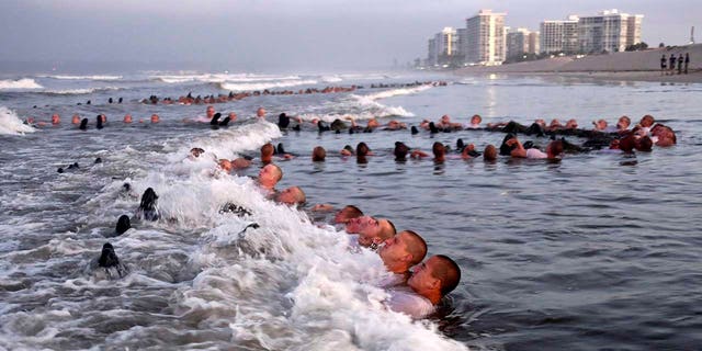 FILE - Questo potrebbe 4, 2020, photo provided by the U.S. Navy shows SEAL candidates participating in "surf immersion" during Basic Underwater Demolition/SEAL (BUD/S) training at the Naval Special Warfare (NSW) Center in Coronado, Calif. NOI. Navy SEALs are undergoing a major transition to improve leadership and expand their commando capabilities. (MC1 Anthony Walker/U.S. Navy via AP)