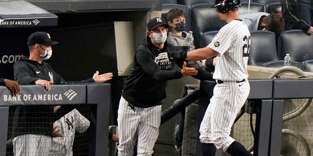 New York Yankees manager Aaron Boone greets DJ LeMahieu (26) at the dugout steps as LeMahieu scored on a bases-loaded walk during the eighth inning of an interleague baseball game against the Atlanta Braves, Tuesday, April 20, 2021, at Yankee Stadium in New York. (AP Photo/Kathy Willens)