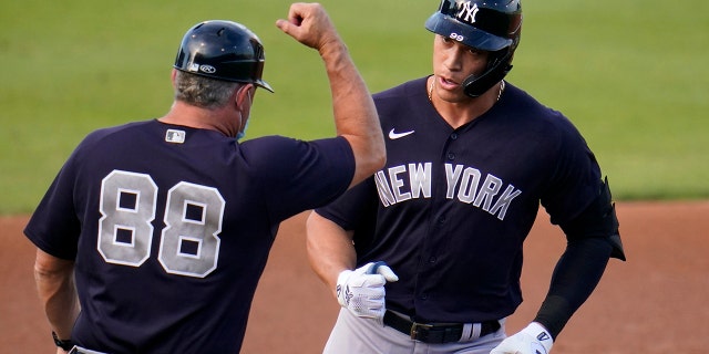 New York Yankees' Aaron Judge, right, rounds third to greetings from coach Phil Nevin after hitting a two-run home run off Philadelphia Phillies starting pitcher Matt Moore during the first inning of a spring training baseball game in Clearwater, Fla., Thursday, March 25, 2021. (AP Photo/Gene J. Puskar)