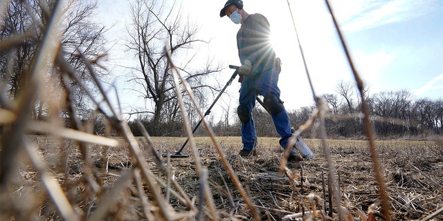 Amateur historian Jim Bailey uses a metal detector to scan for Colonial-era artifacts in a field, Thursday, March 11, 2021, in Warwick, R.I. (AP Photo/Steven Senne)