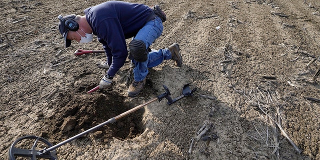 Metal detectorist Jim Bailey scans dirt for Colonial-era artifacts in a field, Thursday, March 11, 2021, in Warwick, R.I.  (AP Photo/Steven Senne)