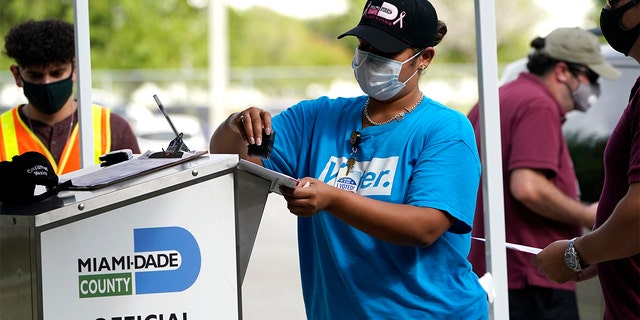 FILE - In this Oct. 26, 2020 file photo, an election worker stamps a vote-by-mail ballot dropped off by a voter before placing it in an official ballot drop box before at the Miami-Dade County Board of Elections in Doral, Fla. (AP Photo/Lynne Sladky, File)