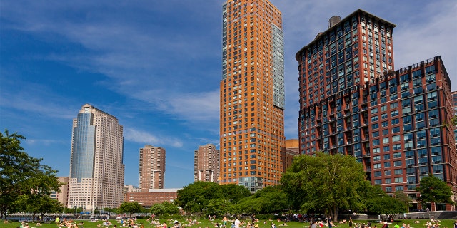Battery Park City with Citygroup building (on the left) in background, Lower Manhattan, New York City. People are relaxing and enjoying a beautiful summer day outside. Wide angle lens.