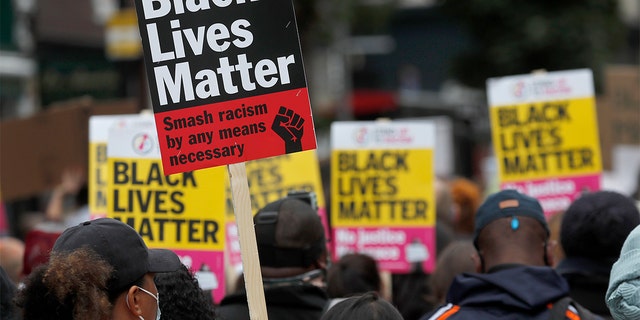 FILE - In this file photo dated Sunday, Aug. 30, 2020, Black Lives Matter protesters hold posters as they march through Notting Hill during the "Million People March" through central London. (AP Photo/Frank Augstein, FILE)