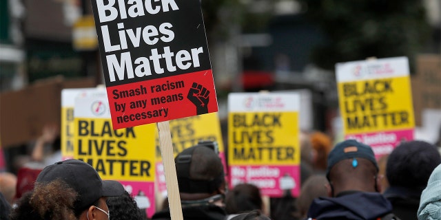 FILE - In this file photo dated Sunday, Aug. 30, 2020, Black Lives Matter protesters hold posters as they march through Notting Hill during the "Million People March" through central London. (AP Photo/Frank Augstein, FILE)