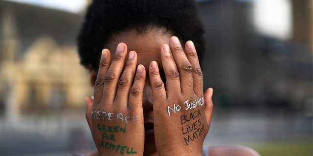 FILE - In this file photo dated Sunday, June 21, 2020, a woman symbolically covers her eyes as she participates in a Black Lives Matter protest calling for an end to racial injustice, at the Parliament Square in central London. (AP Photo/Alberto Pezzali)