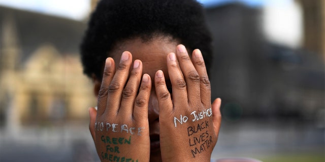 FILE - In this file photo dated Sunday, June 21, 2020, a woman symbolically covers her eyes as she participates in a Black Lives Matter protest calling for an end to racial injustice, at the Parliament Square in central London. (AP Photo/Alberto Pezzali)