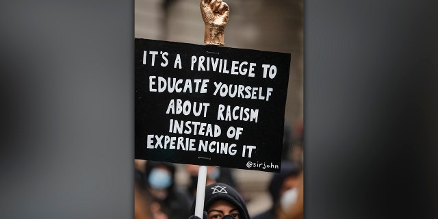 FILE - In this Saturday, June 6, 2020 file photo, a demonstrator holds a placard, during a Black Lives Matter rally in Parliament Square in London, Saturday, June 6, 2020, as people protest against the killing of George Floyd by police officers in Minneapolis, USA. (AP Photo/Frank Augstein, File)