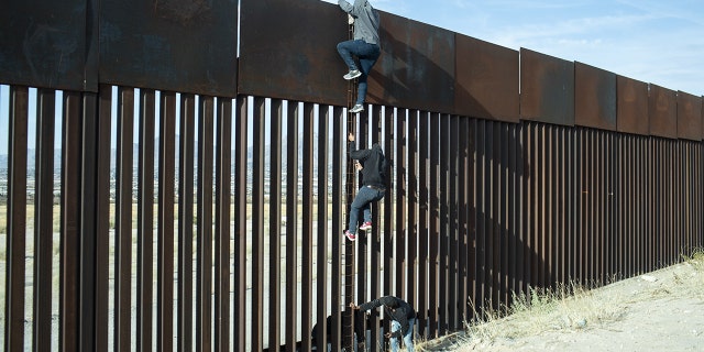 Migrants climb over a border wall in Ciudad Juarez, Mexico, on April 1, 2021.