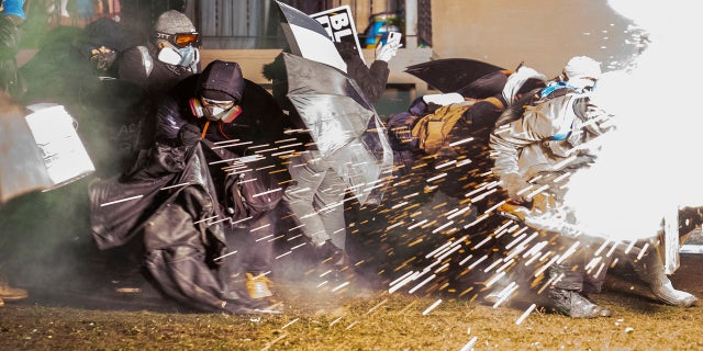 Demonstrators take cover from crowd-dispersal munitions from police outside the Brooklyn Center Police Department while protesting the shooting death of Daunte Wright, late Tuesday, in Brooklyn Center, Minn. (AP)