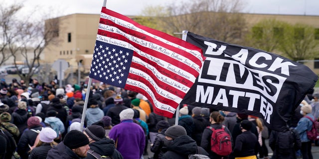 A demonstrator carries a flag bearing the names of people killed by police at a rally outside the Brooklyn Center Police Department Tuesday. (AP)
