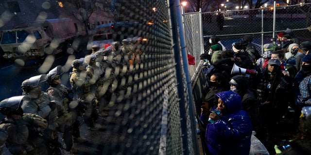 Authorities guard a perimeter fence as demonstrators gather on the other side Tuesday outside the Brooklyn Center Police Department. (AP)