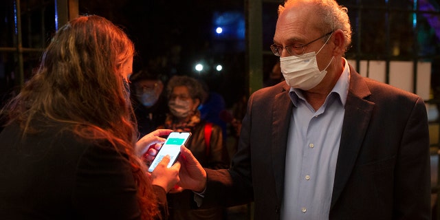 FILE - In this Tuesday, Feb. 23, 2021, file photo, a man presents his "green passport," proof that he is vaccinated against the coronavirus, on opening night at the Khan Theater for a performance where all guests were required to show proof of vaccination or full recovery from the virus, in Jerusalem. (AP Photo/Maya Alleruzzo, File)